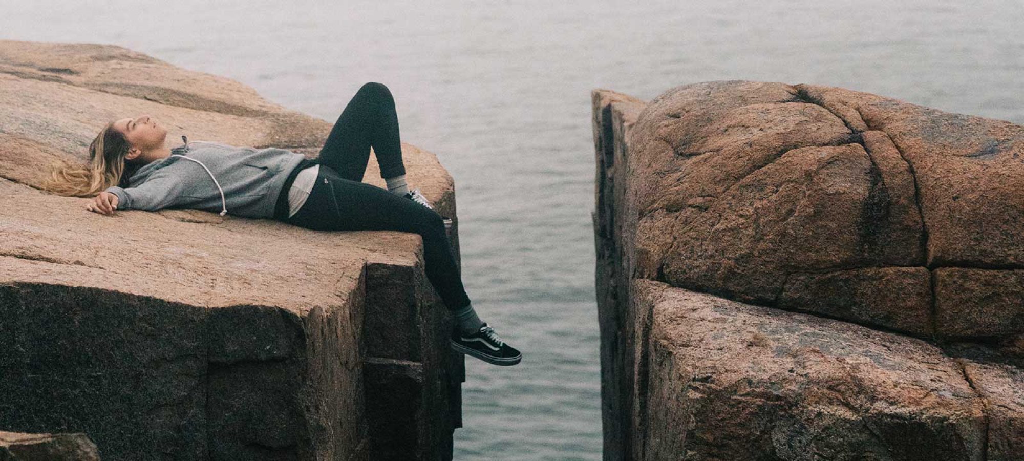 Woman laying on rocks beside ocean